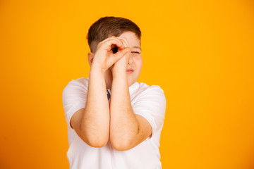 The boy looks like through binoculars. Hands folded into a straw. Boy is watching looking through...