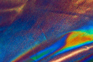 iridescent holographic fabric background blurred in red shades of rainbow colors