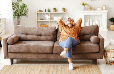Senior woman listening to music sitting on sofa.
