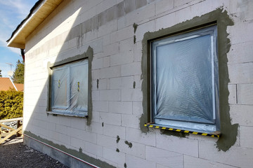 Windows of a house under construction covered with protective plastic film.