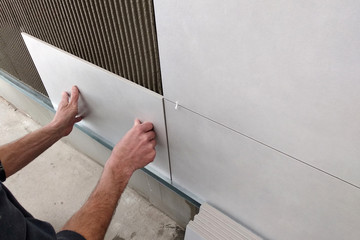 Worker hands putting ceramic tiles on the wall.