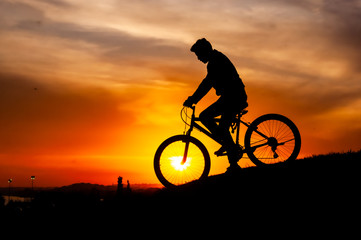 Fototapeta na wymiar silhouette of people riding on the hill at sunset. magic hour silhouette of bicycle