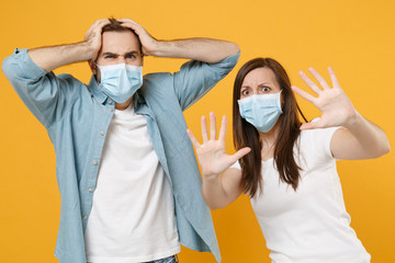 Two people in sterile face masks white t-shirts isolated on yellow background studio. Epidemic...