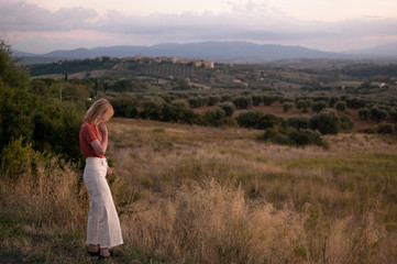 Fototapeta na wymiar Young woman in Tuscany landscape in Italy during the sunset with warm colors