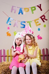 children-happy little cute girl friends holding an Easter cake and smiling on the background of the Easter decor