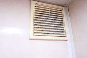 Extremely dirty and dusty white plastic ventilation air grille at home close up, harmful for health, house cleaning concept.