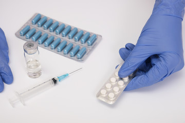 A doctor in blue nitrile gloves holding a blister of pills, capsules close up, medicament and remedy treatment concept