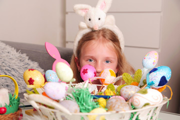Cute happy little child girl in bunny ears with Easter eggs basket at home. Happy Easter