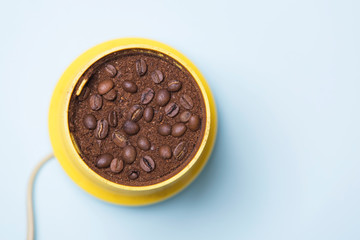 Yellow coffee grinder with coffee and beans, top view
