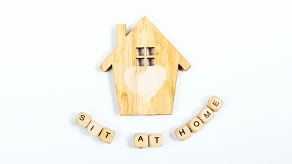 Wooden children's house, on wooden cubes text SIT AT HOME, concept