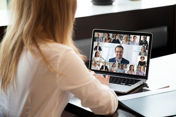 Pc screen view over woman shoulder at group video call. Visual communication between engaged diverse people distantly using webcam and laptop internet connection app. International remote chat concept - obrazy, fototapety, plakaty