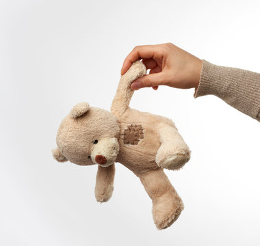 Naklejki female hand holds small beige cute teddy bear with patches