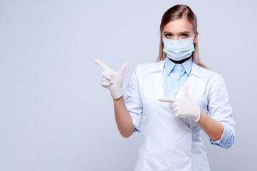 Nurse in medical gloves and a mask. Doctor points a finger to the side. Isolated