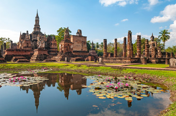 Fototapeta na wymiar The Wat Mahathat temple reflecting in a pond with lotus flowers, Sukhothai, Thailand. 