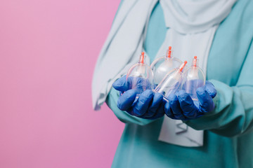 A girl in a scarf holds in her hands jars for hijama. Vacuum pumps Dropping