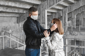 Fototapeta na wymiar A man puts a protective mask on a woman's face. The Coronavirus, Covid-19