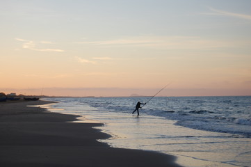 Fototapeta na wymiar fisherman in action at sunset on the beach
