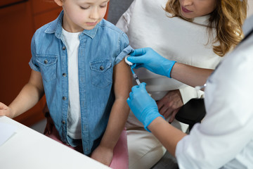 Caucasian brave girl getting injection in pediatric office