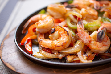 A view of a skillet of shrimp fajitas, in a restaurant or kitchen setting.