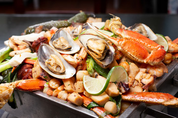 A closeup view of a tray full of several varieties of seafood in a restaurant or kitchen setting.