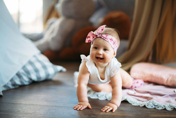 A small baby, a girl, is happily crawling on the floor
