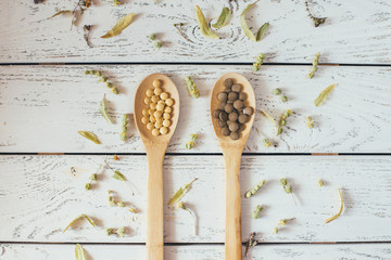 Herbal pills and dry herbs on wooden background.