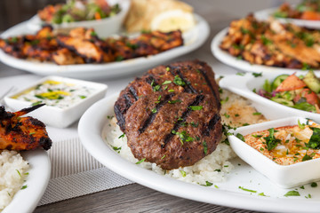 A view of several Mediterranean dishes in a restaurant or kitchen setting, featuring kafta and shish kabob.