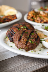 A view of several Mediterranean dishes in a restaurant or kitchen setting, featuring kafta and shish kebob.