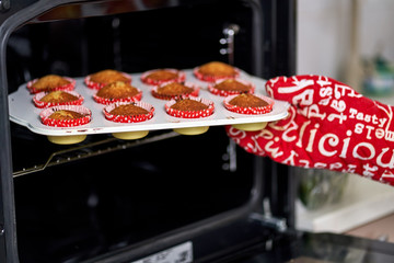 Woman taking muffins out of the oven