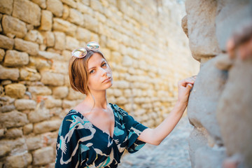 A girl in a straw hat and dress walks in Carcassonne