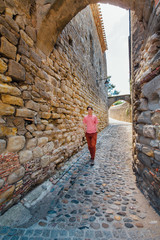 A young man runs against a wall on a street in the medieval city of Carcassonne in France