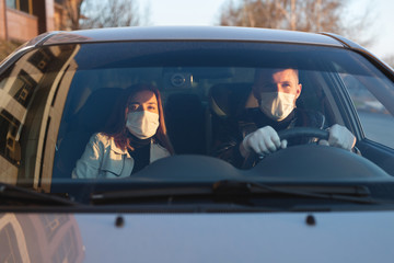 A man and a woman wearing medical masks and rubber gloves to protect themselves from bacteria and viruses while driving a car. masked men in the car. coronavirus, covid-19