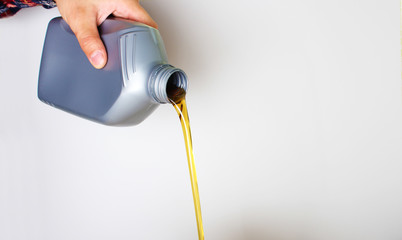 automotive oil in a hand a gray bottle on a light background