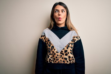 Fototapeta premium Young beautiful woman wearing casual sweatshirt standing over isolated white background making fish face with lips, crazy and comical gesture. Funny expression.