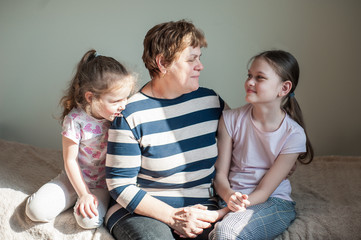 Closeup portrait of a happy grandmother and her granddaughters inside. The concept of family values.