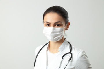 Caucasian young doctor posing for camera against light background