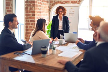 Group of business workers smiling happy and confident in a meeting. Working together looking at presentation using board and charts at the office.