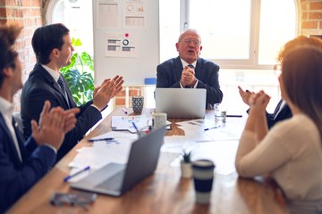 Group of business workers smiling happy and confident in a meeting. Working together looking at presentation using board and laptop applauding at the office.
