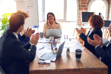 Group of business workers smiling happy and confident in a meeting. Working together looking at presentation using board and laptop applauding at the office.