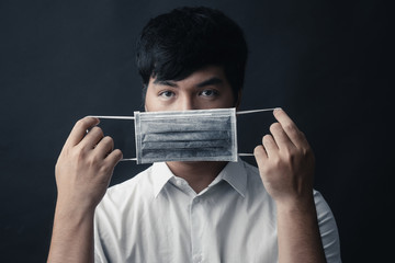 Asian man with medical mask on his face in black background - Studio portrait