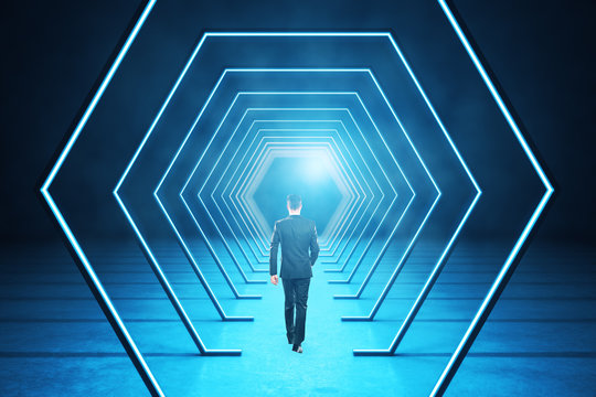businessman walking in modern blue interior with abstract luminous hexagon corridor.