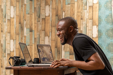 young black man working with his laptops at home laughing