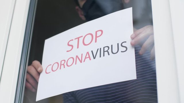 Stop coronavirus. Man holding a sign in the window