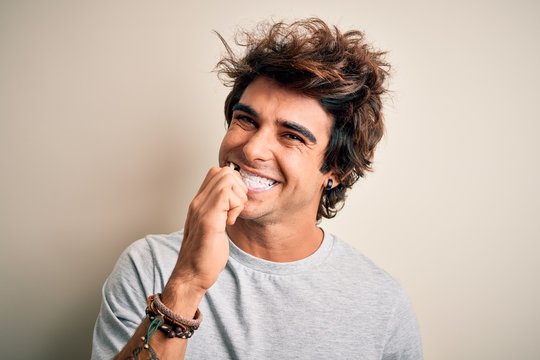 Young handsome man smiling happy. Standing with smile on face whasing tooth using toothbrush over isolated white background