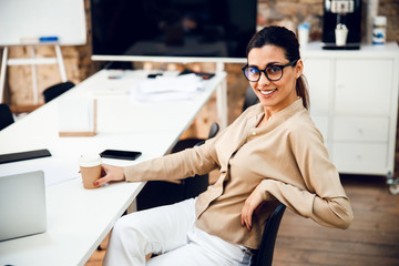 Beautiful young woman sitting at the table in office