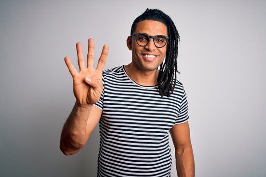 Young handsome african american man with dreadlocks wearing striped t-shirt and glasses showing and pointing up with fingers number four while smiling confident and happy.