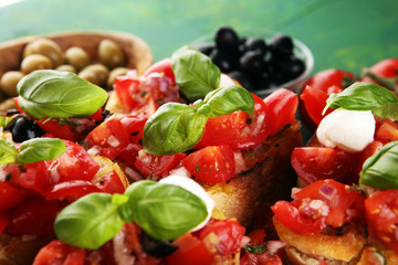Bruschettas on cutting board on rustic background with tomatoes and basil