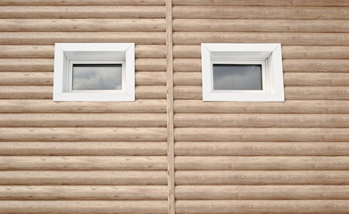Fototapeta na wymiar two symmetrical small windows on the wall of the house.