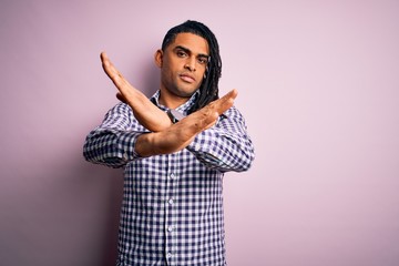 Young handsome african american afro man with dreadlocks wearing casual shirt Rejection expression crossing arms doing negative sign, angry face