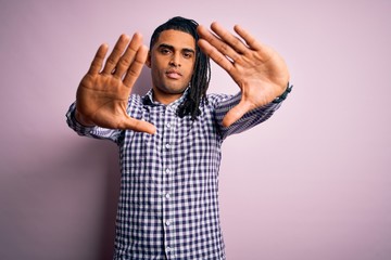 Young handsome african american afro man with dreadlocks wearing casual shirt doing frame using hands palms and fingers, camera perspective